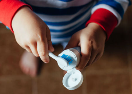 Child putting toothpaste on a toothbrush